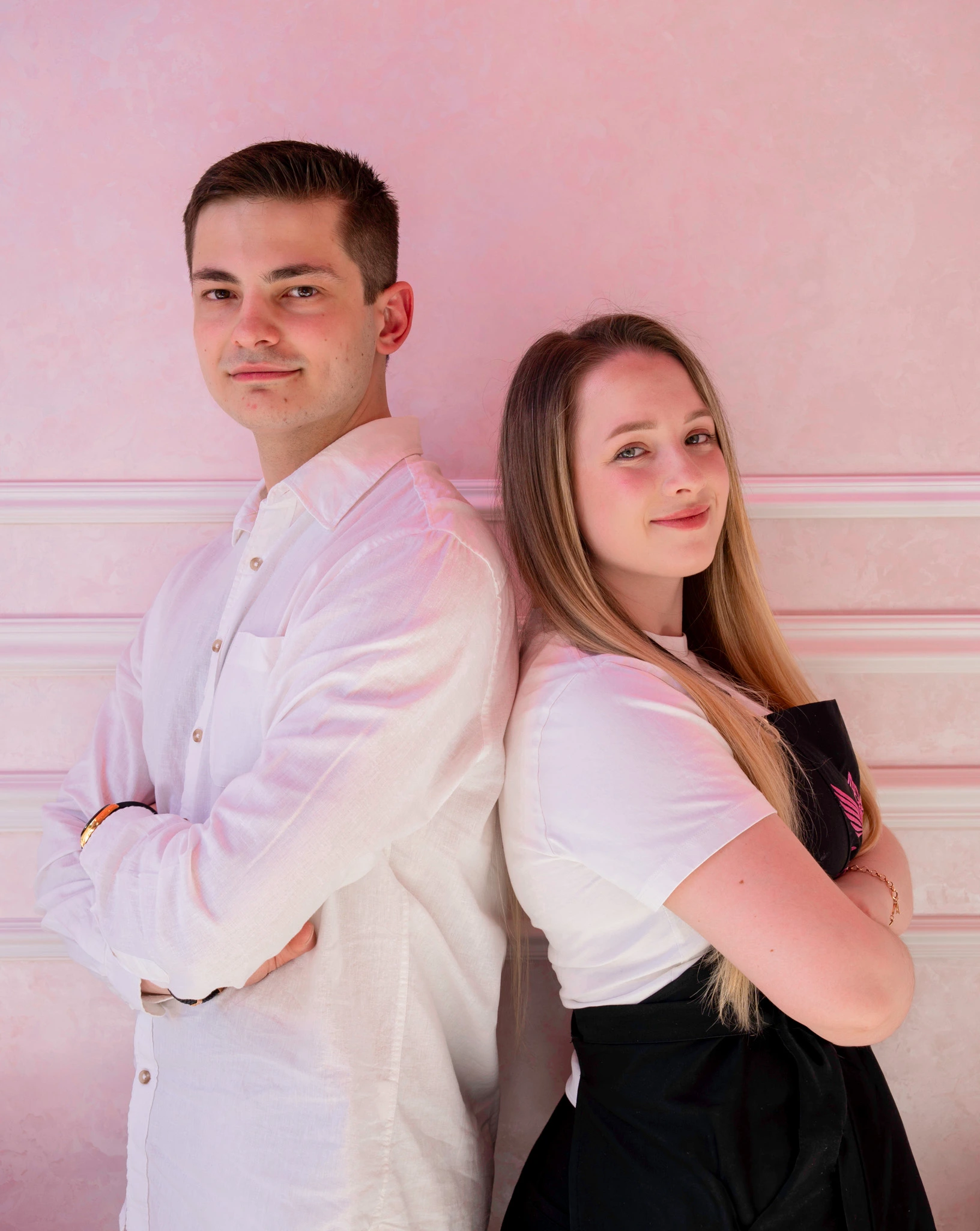 Grundarna av Angel Cakes & Coffee står rygg mot rygg framför caféets rosa vägg