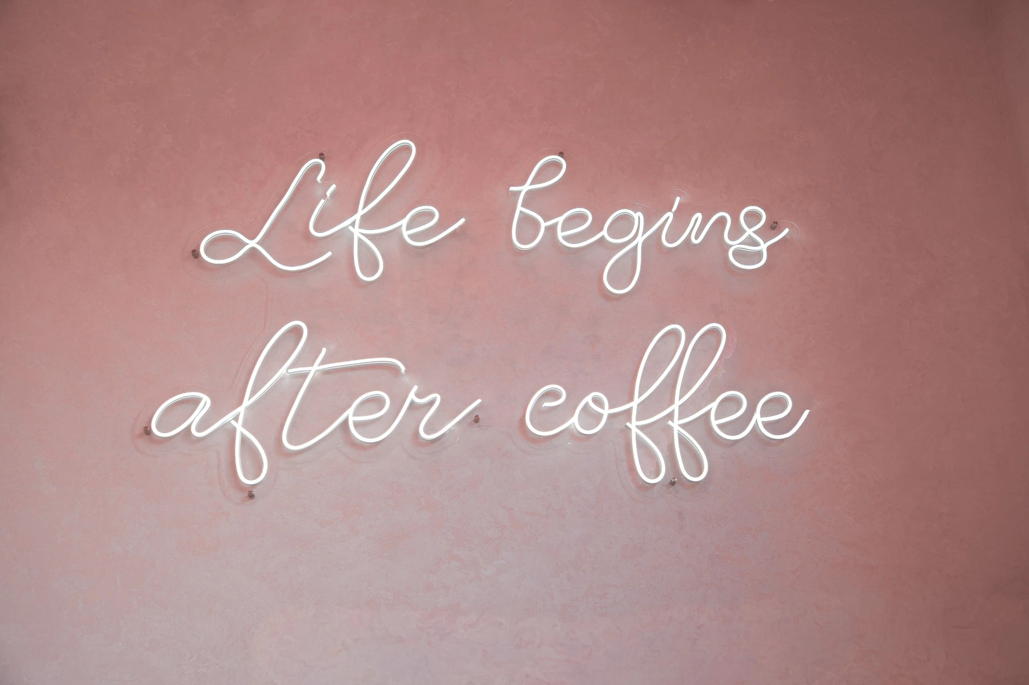Vit neonskyllt med texten Life begins after coffee på caféets vägg
