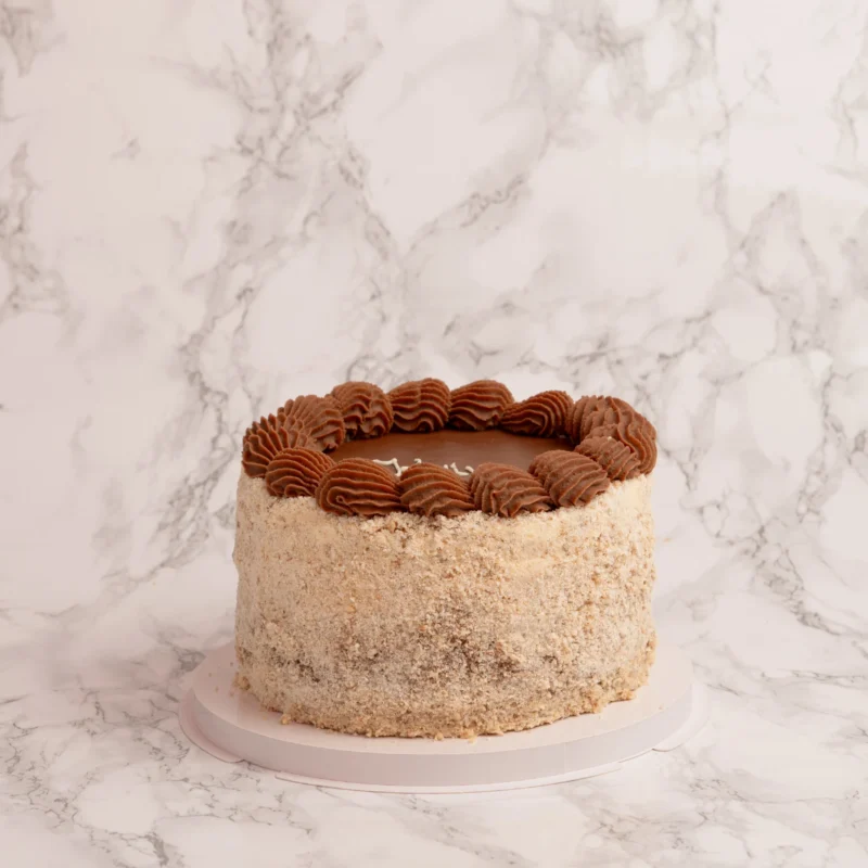 Hel Kyivtårta framifrån med nötsmulssida och chokladtopp mot marmorbakgrund