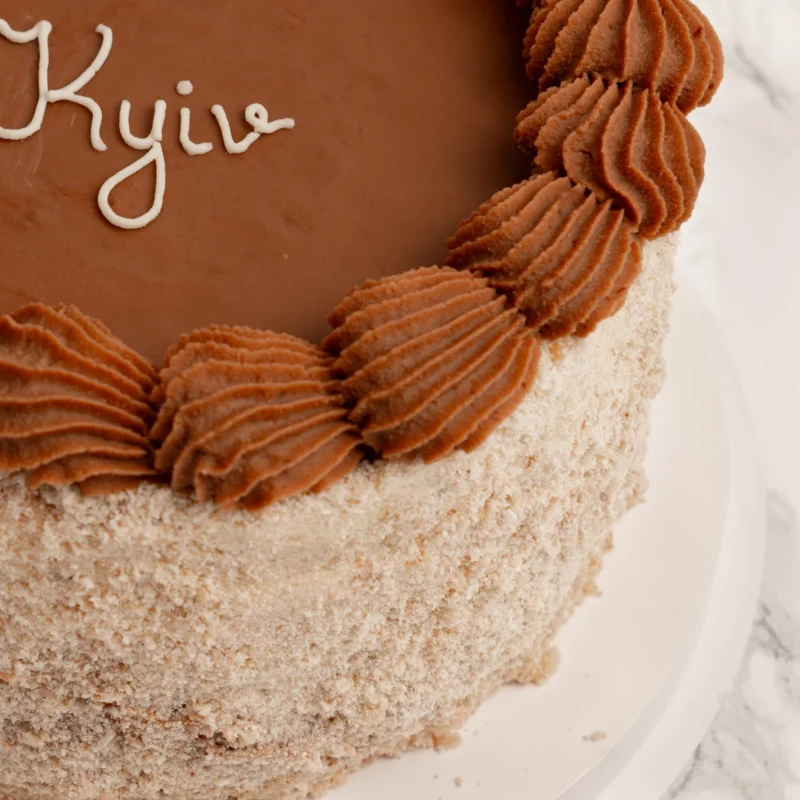 Kyivtårta - Angel Cakes & Coffee Närbild på Kyivtårta med chokladglasyr, spritsat chokladsmör och nötkaksmuletäcke
