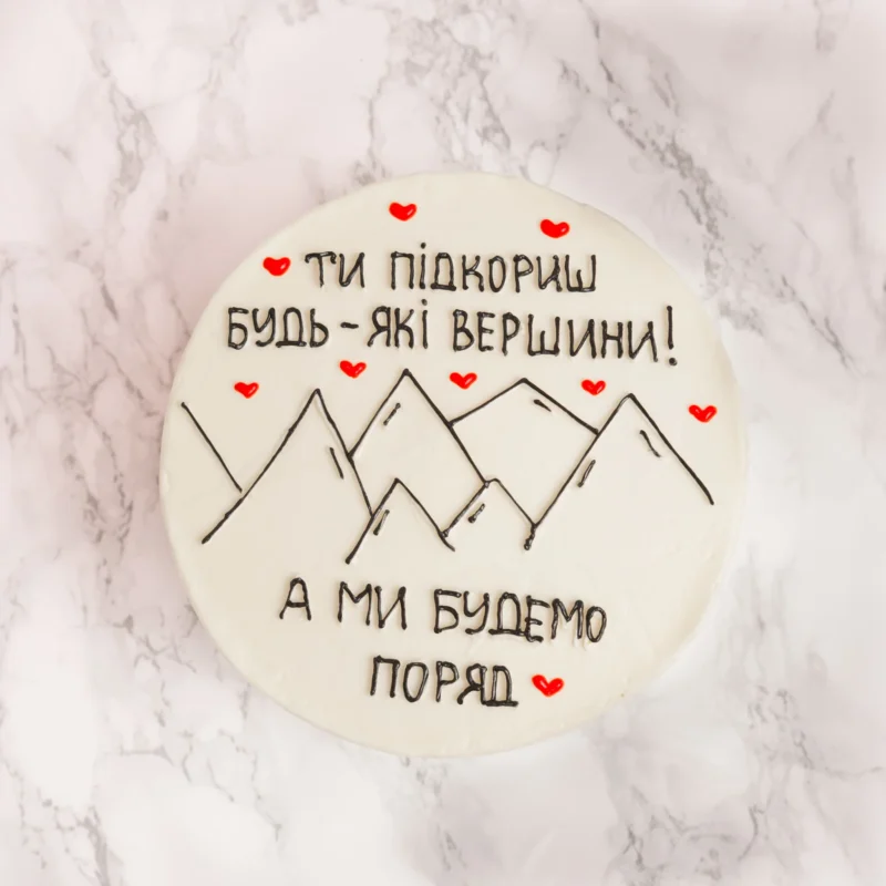 Mountain tårta fotograferad rakt ovanifrån med bergsmotiv och ukrainsk text med röda hjärtan