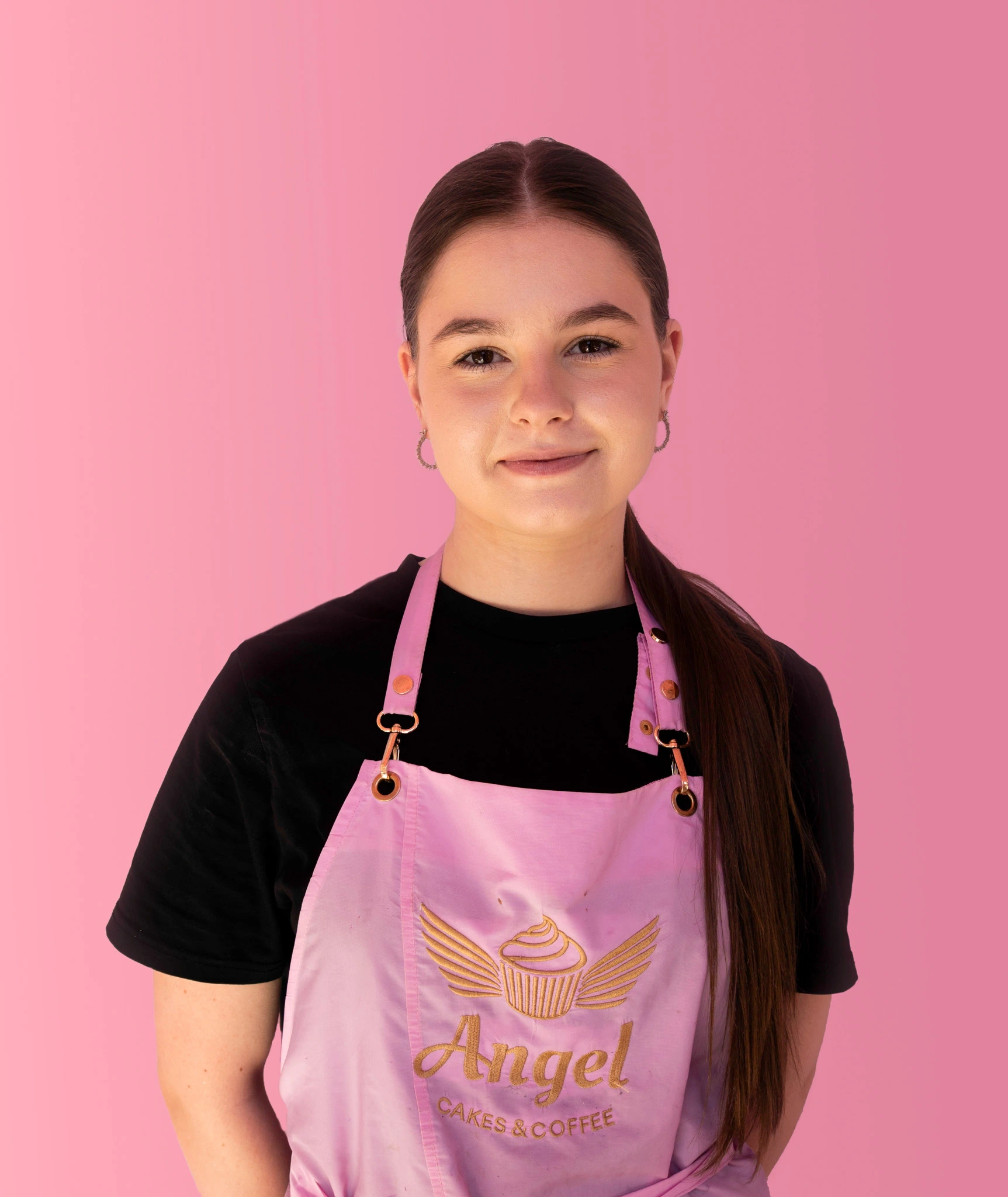 Medarbetare på Angel Cakes & Coffee iklädd rosa förkläde med logotyp