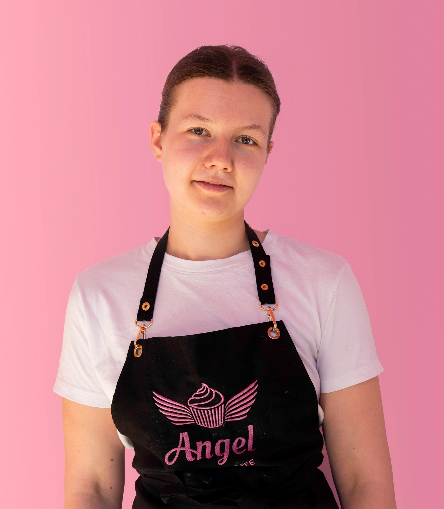 Medarbetare på Angel Cakes & Coffee iklädd svart förkläde med logotyp