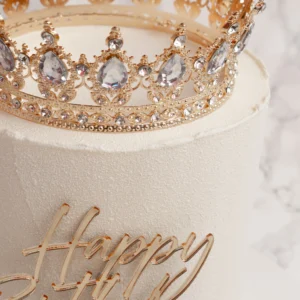 Närbild på Princess tårtas guldkrona med kristaller och Happy Birthday-topper i guld