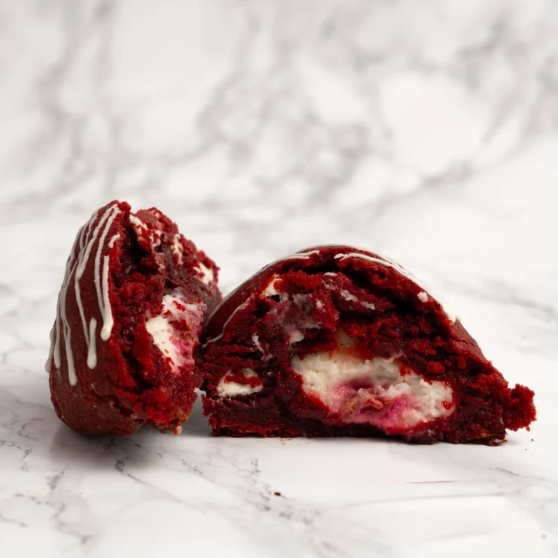 Red velvet cookie delad på mitten med cream cheese-fyllning synlig inuti