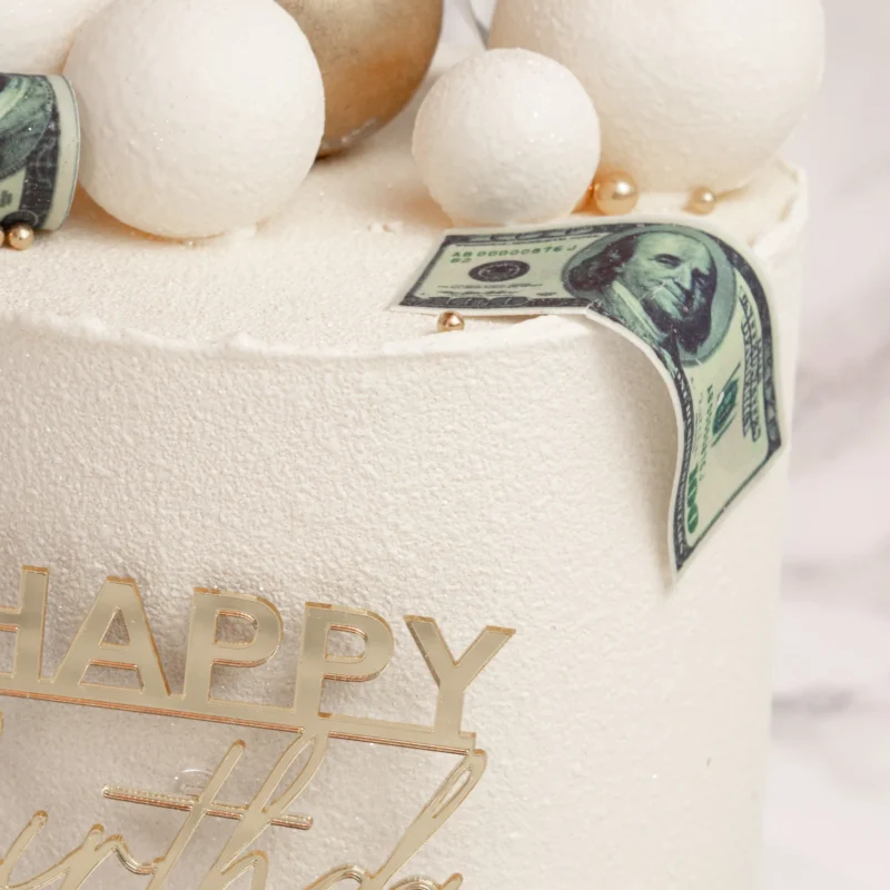 Närbild på Spheres & Dollars tårta med dollarsedlar och Happy Birthday-topper i guld