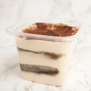 Tiramisu i förpackning med synliga lager av mascarpone och espressoindränkta ladyfingrar, toppat med kakaopulver