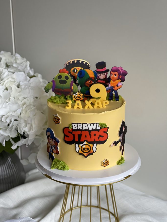 Födelsedagstårta med figurer från Brawl Stars och dekorativt godis.
